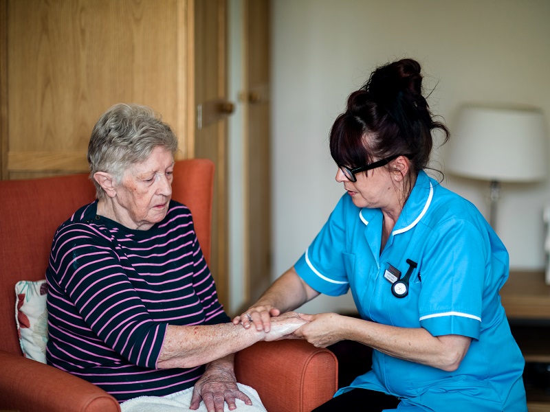 Carer giving hand massage to resident